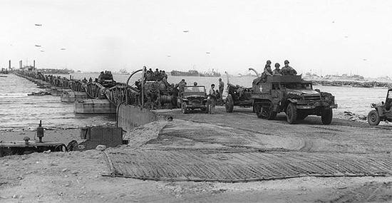 Picture illustrating one of the piers of the Omaha Beach Artificial Harbor taken some time around mid June 1944. The personnel of the 107th Evacuation Hospital landed at Omaha Beach, Normandy, France, on 12 July 1944.