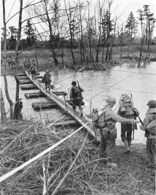 Soldiers of the 1st Infantry Division, with elements of the 1st Medical Battalion cross the Ruhr River on a pontoon bridge. Photograph taken 25 February 1945. 