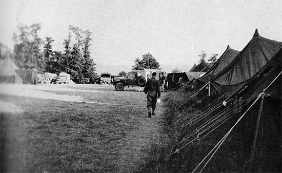 Partial view of the 34th Evacuation Hospital’s set up near Carentan, France. Ambulance unloading casualties at the Receiving. Photo taken some time between 5 July and 6 August 1944.