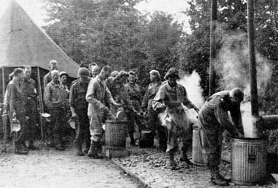 Daily scene taken at La Haye-du-Puits, Normandy, France. After enjoying chow, male and female personnel wash, rinse and clean their mess kits in the corresponding immersion containers. Picture taken some time during September 1944.